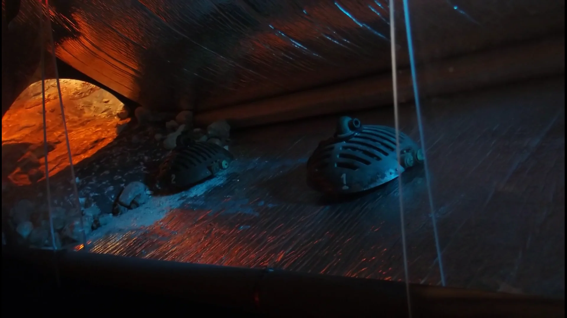 A small scavenger machine entering a blue-lit industrial interior.